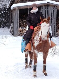 painted horse lännenratsastusvarusteissaan nainen selässään talvella